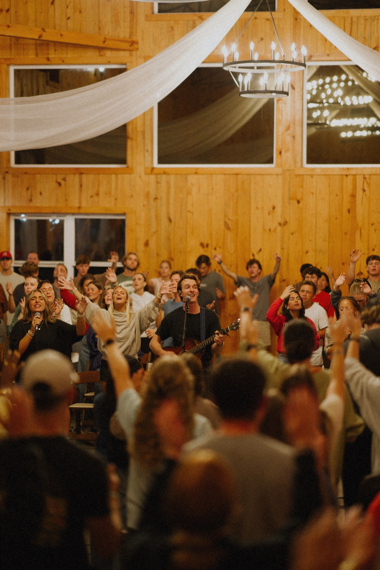 Worship night crowd gathered in large venue, hundreds of people in worship